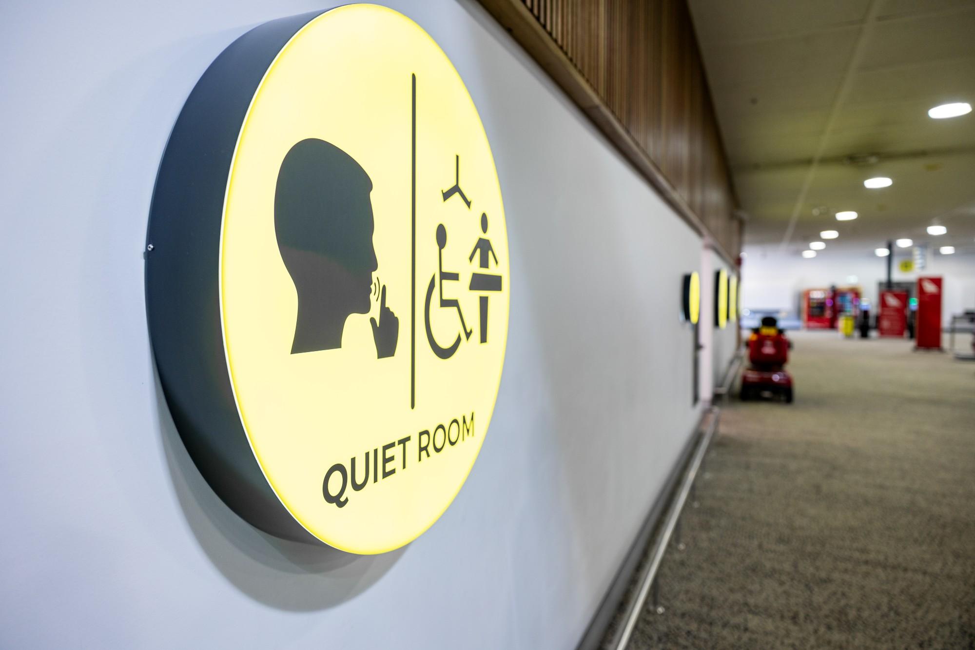 Circular yellow sign inside Townsville Airport indicating Quiet Room with accessibility and rest icons.