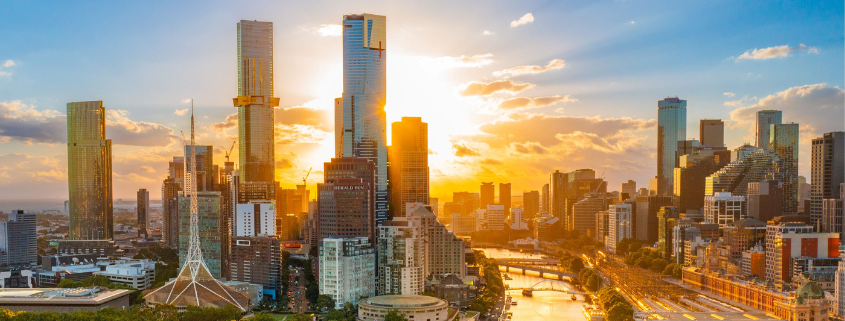 Melbourne cityscape at sunset with skyscrapers, Yarra River, and bridges under golden light.