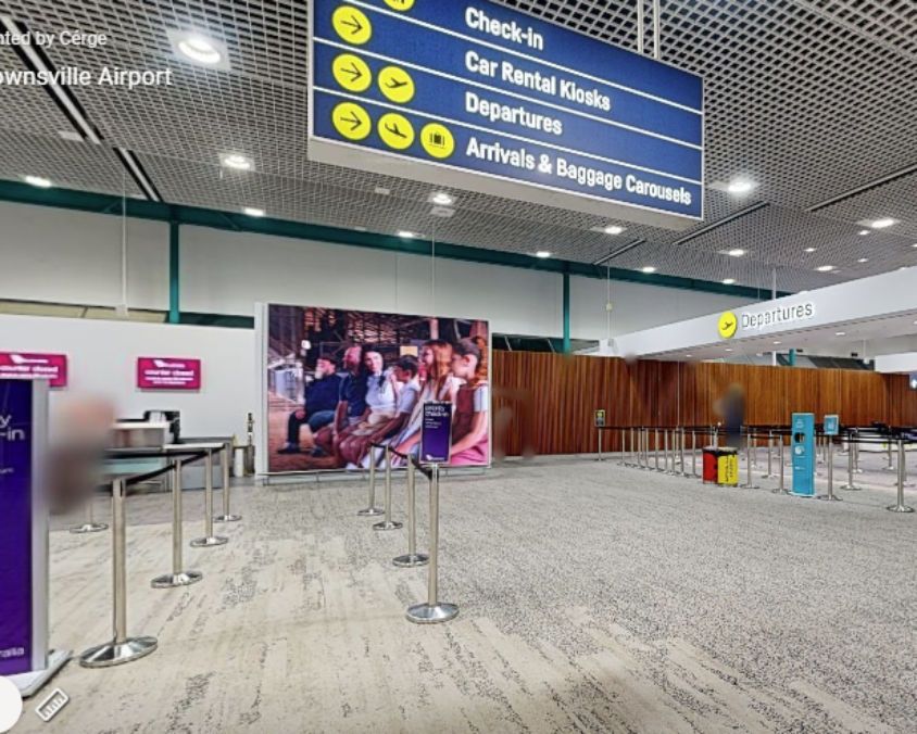 Townsville Airport interior near check-in and security with directional signs, priority queue area, and overhead lighting.