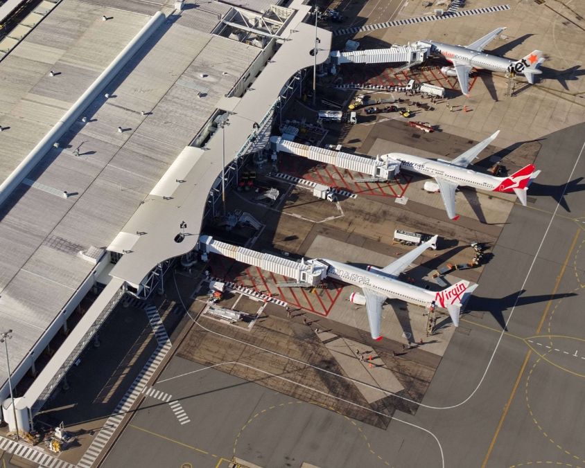 Aerial view of a terminal at Townsville Airport with Virgin Australia, Qantas, and Jetstar planes parked at gates. 
