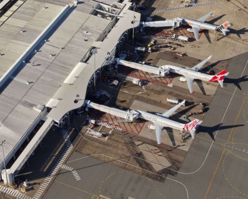 Aerial view of a terminal at Townsville Airport with Virgin Australia, Qantas, and Jetstar planes parked at gates. 