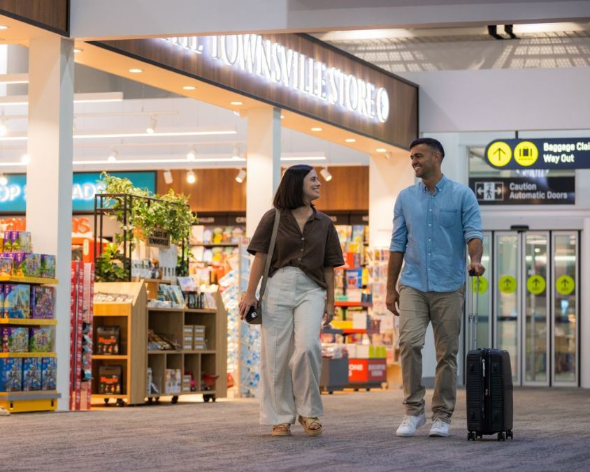Townsville Airport terminal scene with two travelers walking past ‘The Townsville Store. 