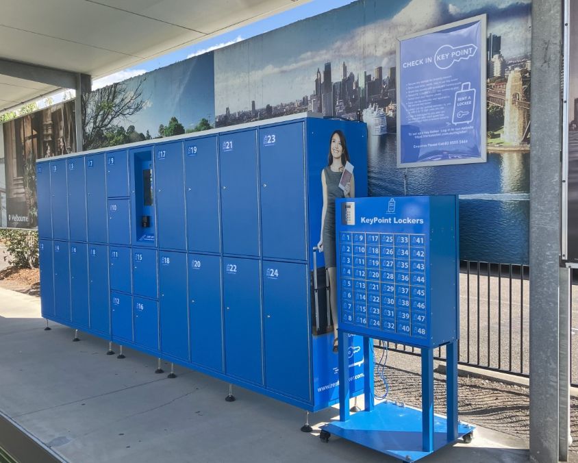 Outdoor RentALocker check-in area with blue KeyPoint Lockers, mural backdrop, and instructional signage.