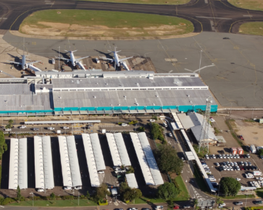 Aerial view of Townsville Airport terminal with parked aircraft, parking lots, and surrounding runways and taxiways.
